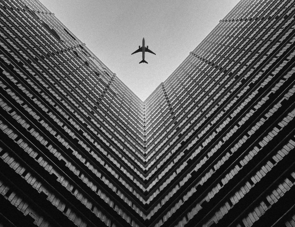 Aeroplane flying over modern office buildings.