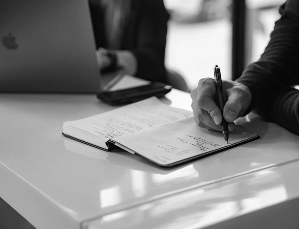 Close up of man taking notes on a pad in a meeting.
