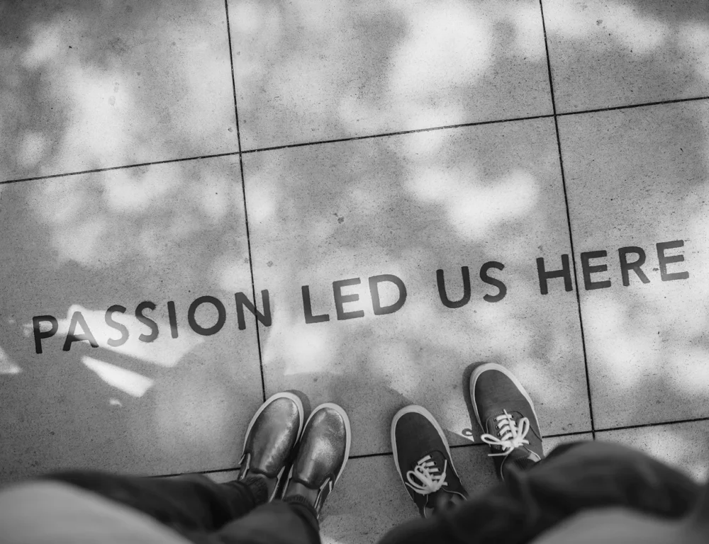 Two people standing over a message on the floor that reads passion led us here.